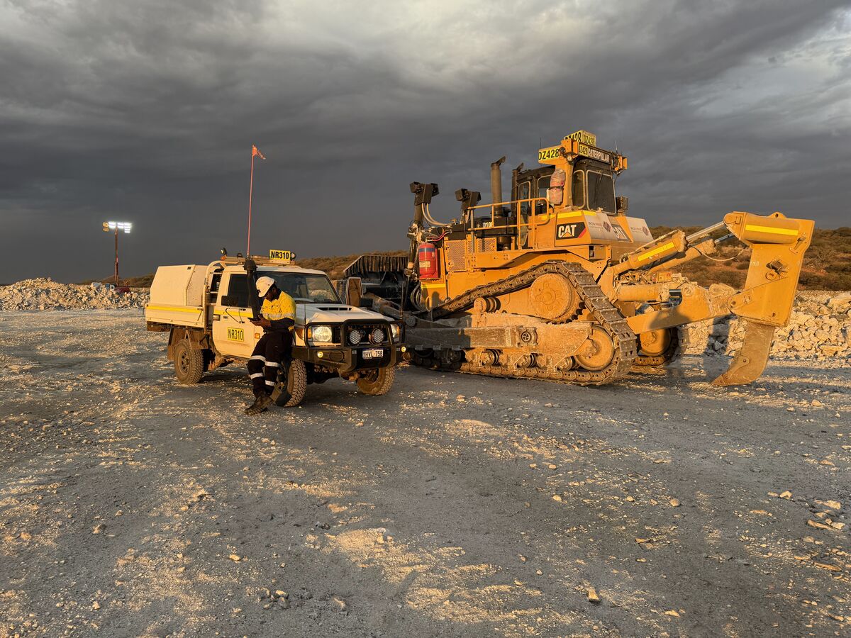 Fitter working on a dozer under lights at night on a mine site