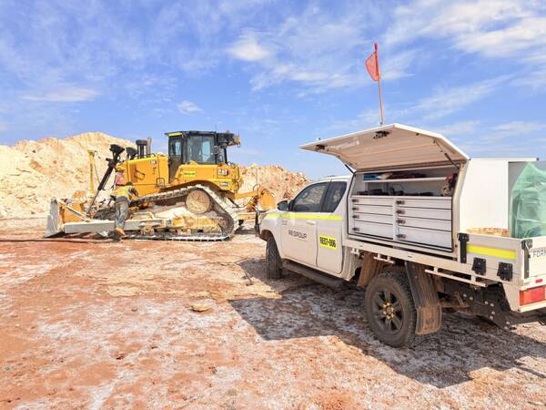 Mine-spec service ute parked beside a dozer on a salt flat