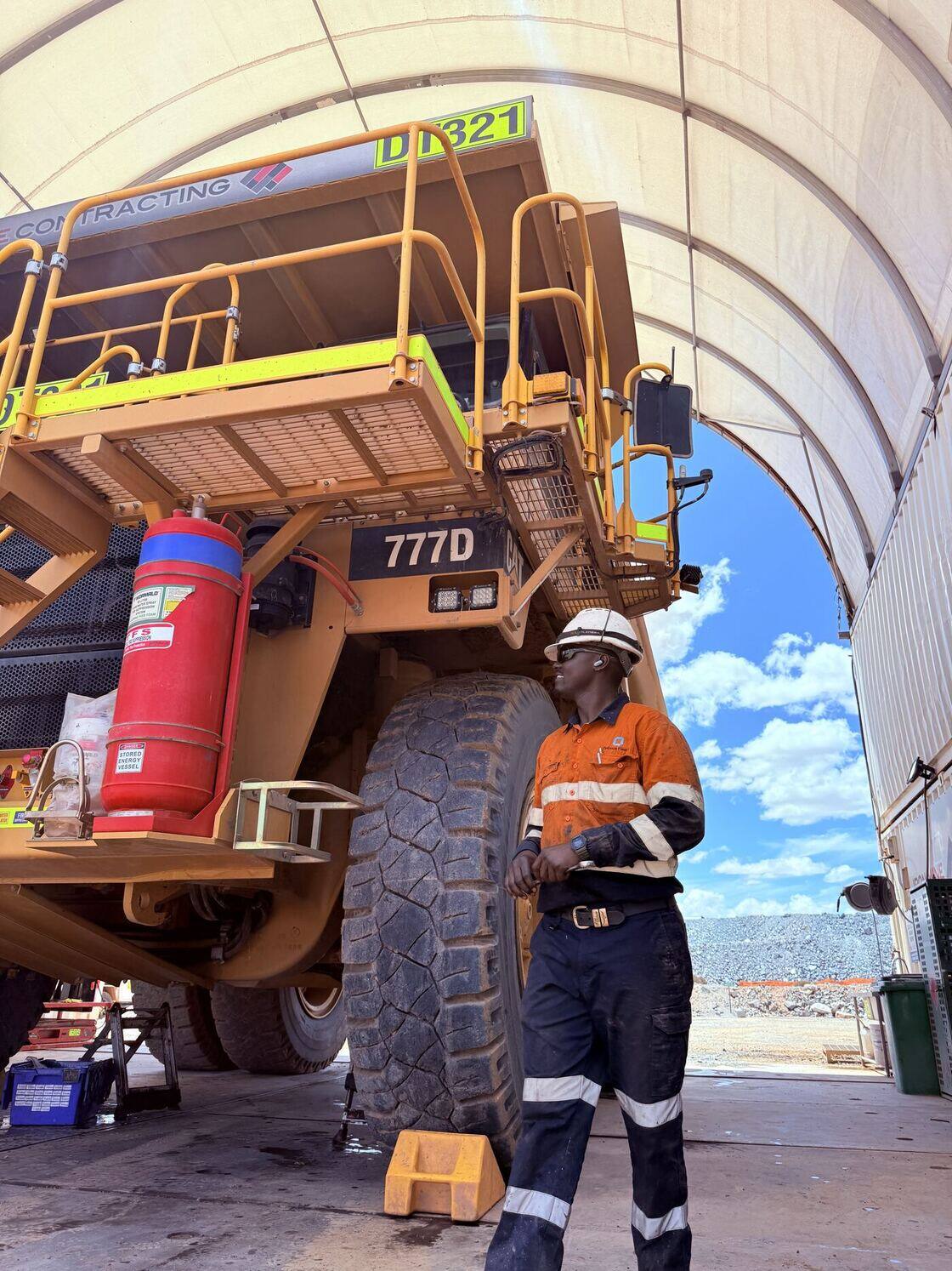 Fitter standing beside the wheel of a 777 haul truck in a mine site workshop