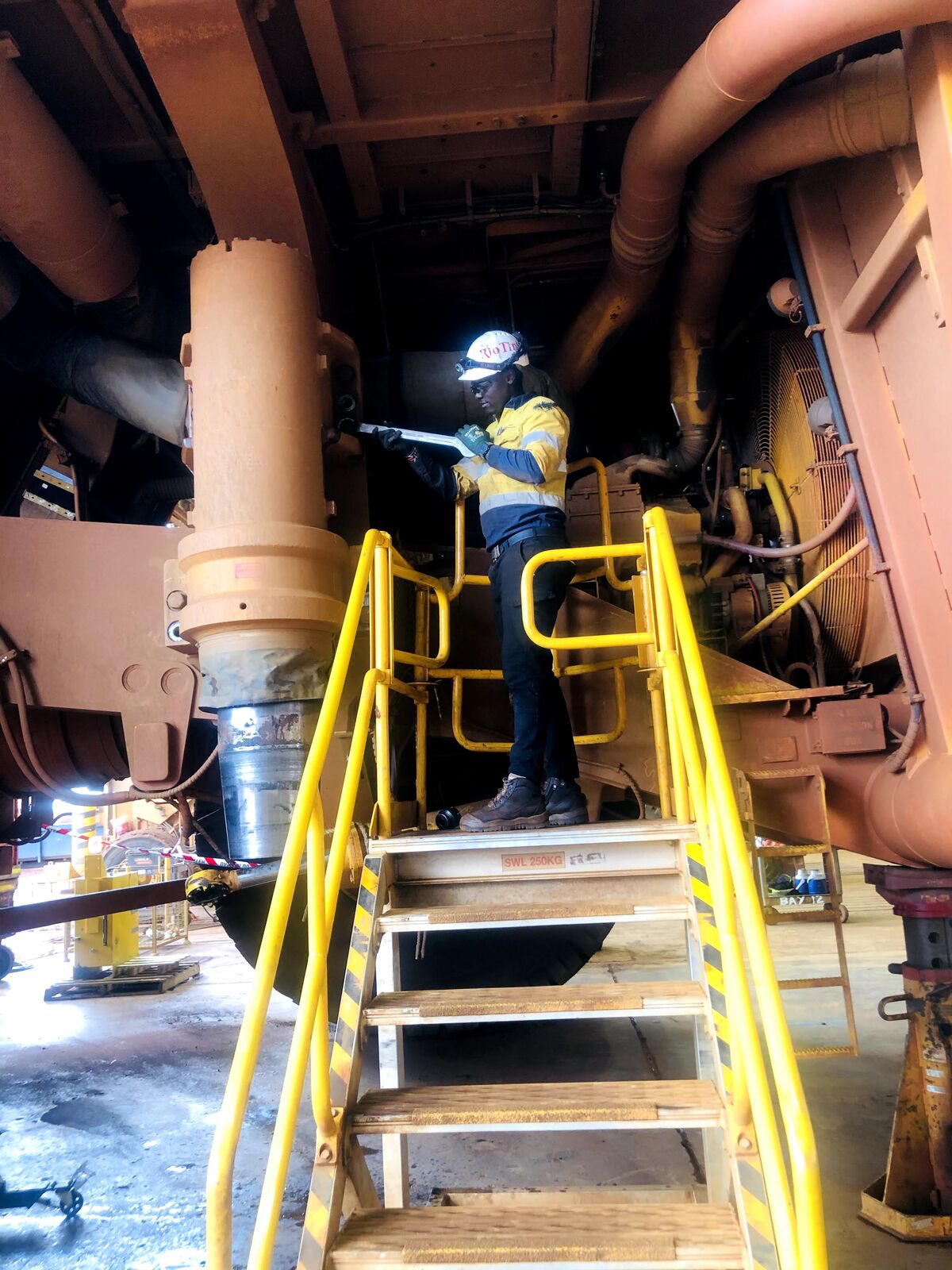 Fitter working on a platform inside the frame of a haul truck