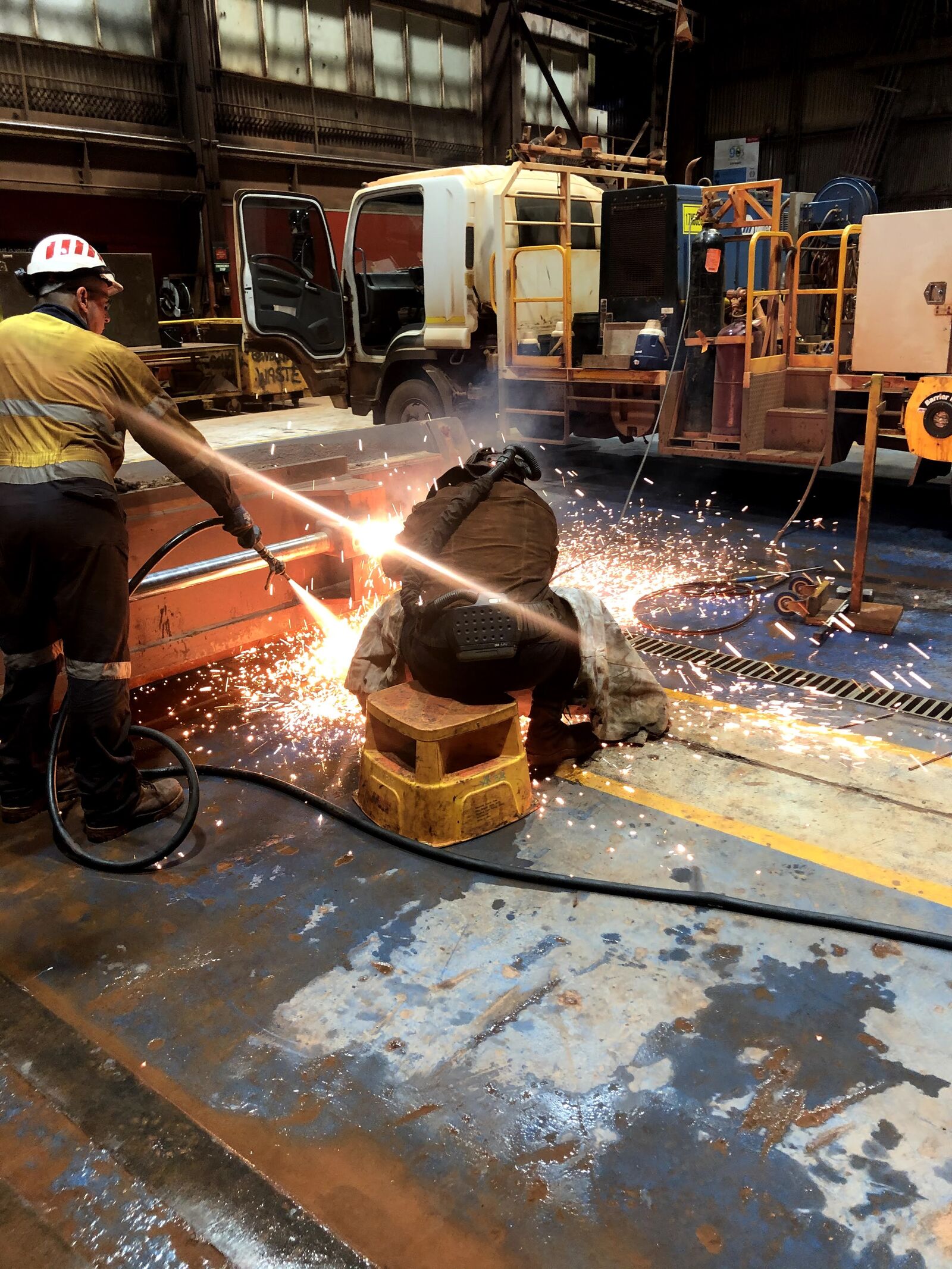 Fitter cutting steel with an oxy torch in a heavy machinery workshop